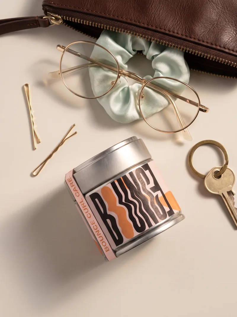 A Bounce tin in a flat lay with glasses, keys and hair clips